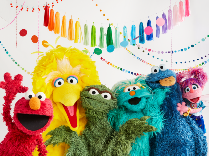 Elmo, Ernie, Bert, Big Bird, Oscar the Grouch, Rosita, Cookie Monster, Grover, and Rosita all pose together for a group photo.